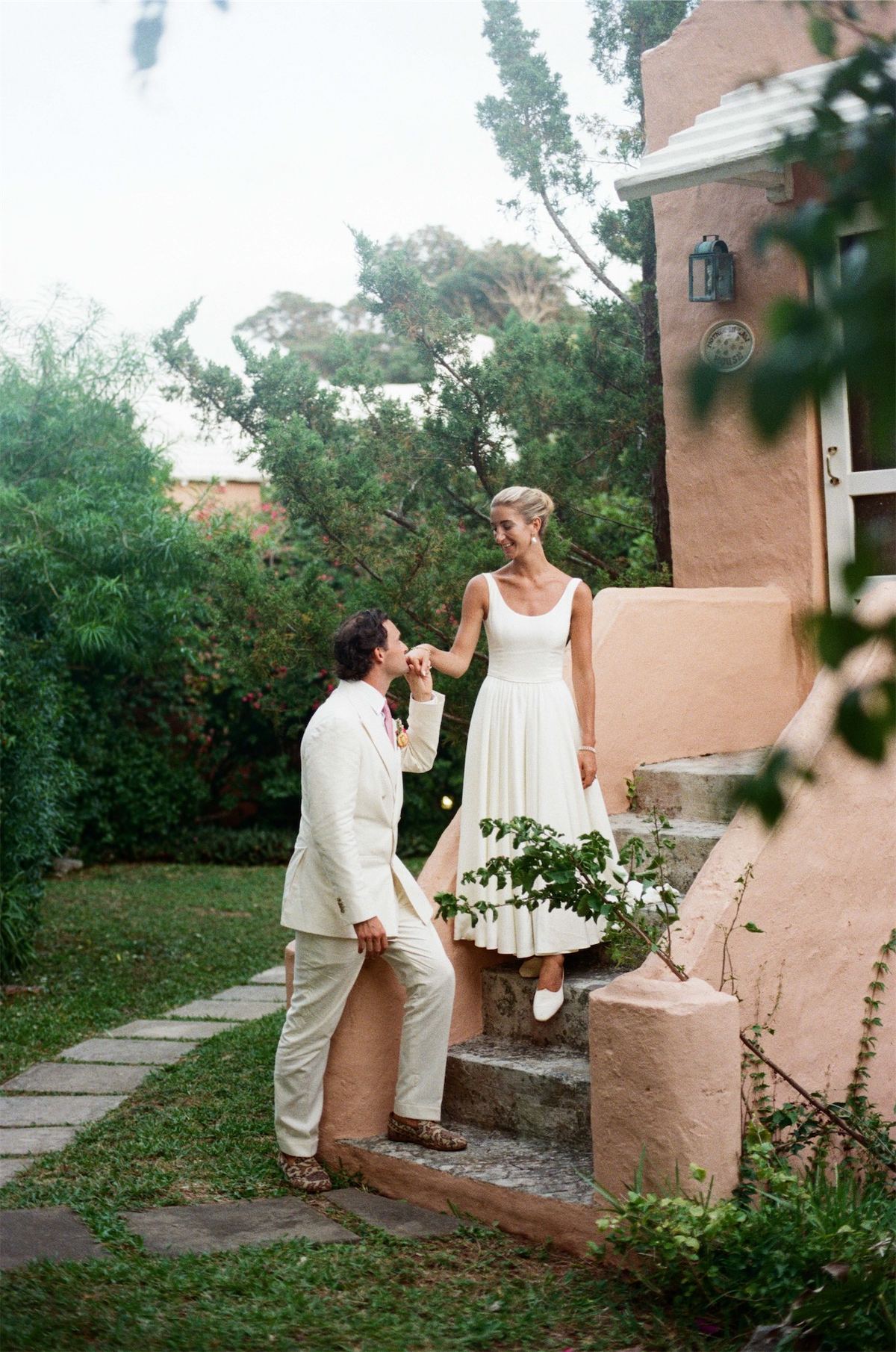 Bride and groom on the steps of a coral pink island house