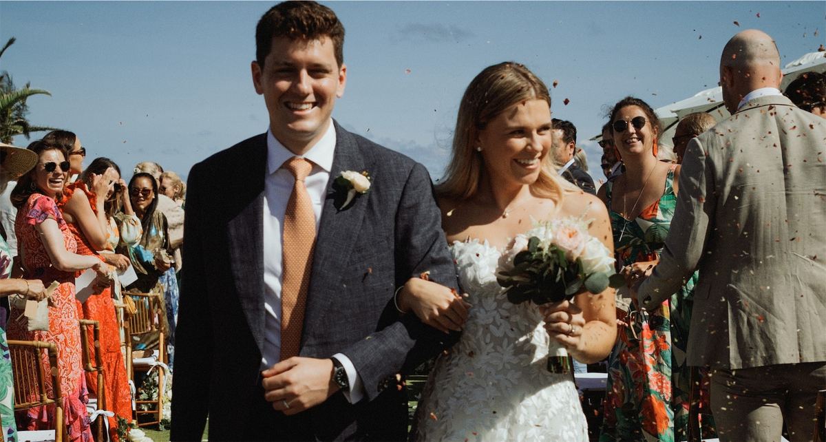 Bride and groom walking back down the aisle as guests shower them with confetti