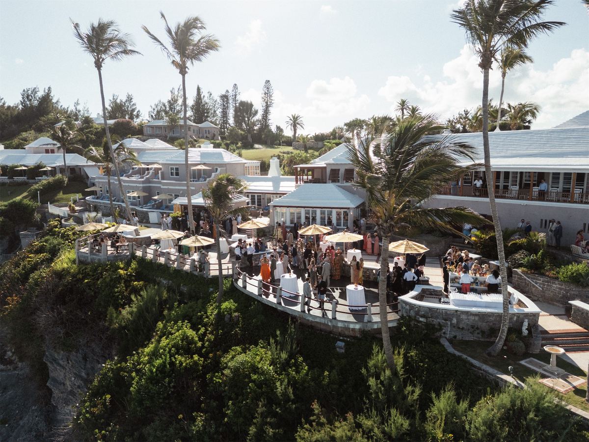 Clifftop cocktail hour with parasols and palms above the turquoise sea