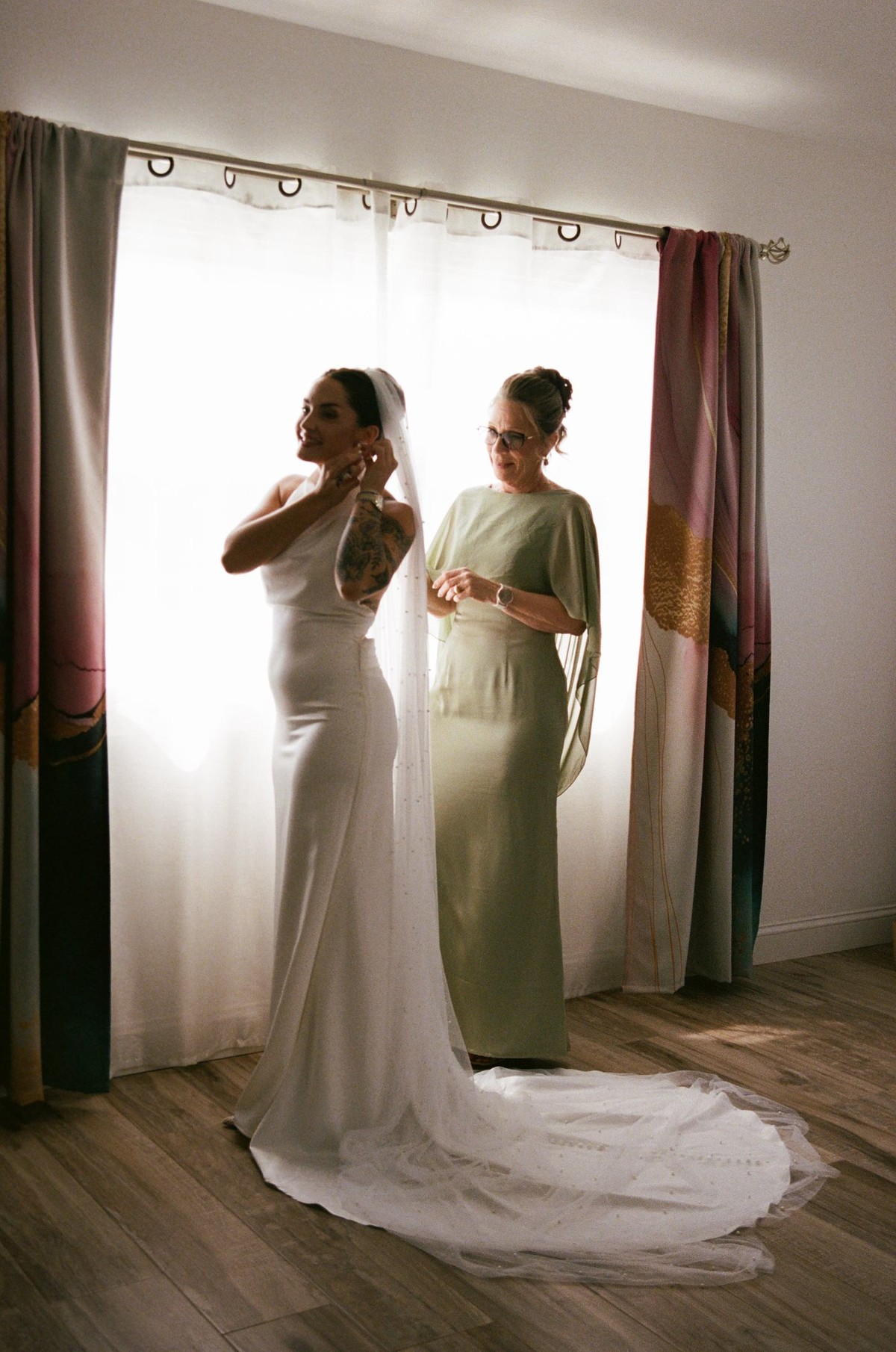 Bride and her bridesmaid in the window light while getting ready, shot on film