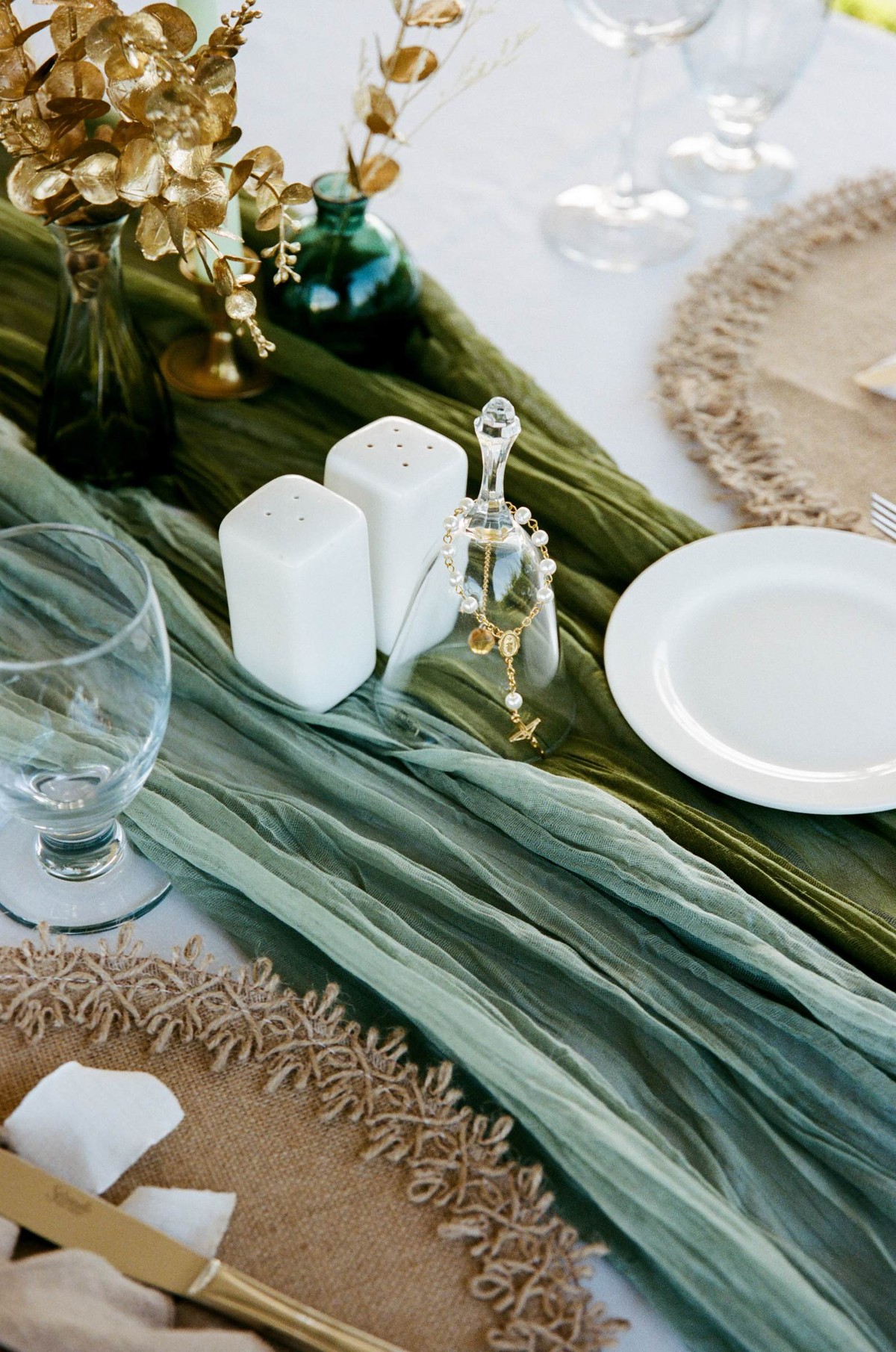 Reception table detail with a green runner and gold flowers, shot on film