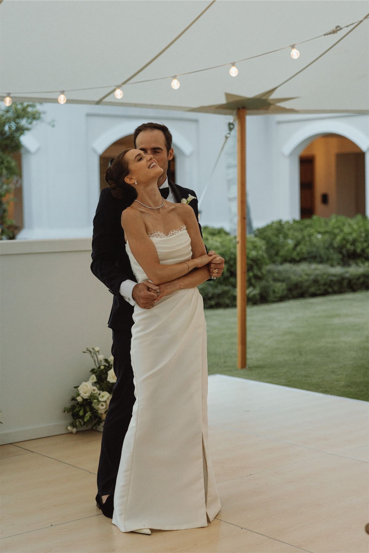 Bride and groom holding each other on the tented dance floor at dusk