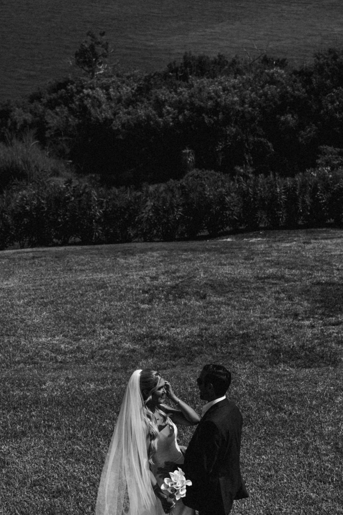 Cam lifts Paige's veil on the darkened lawn on Hawkins Island, Bermuda, black and white