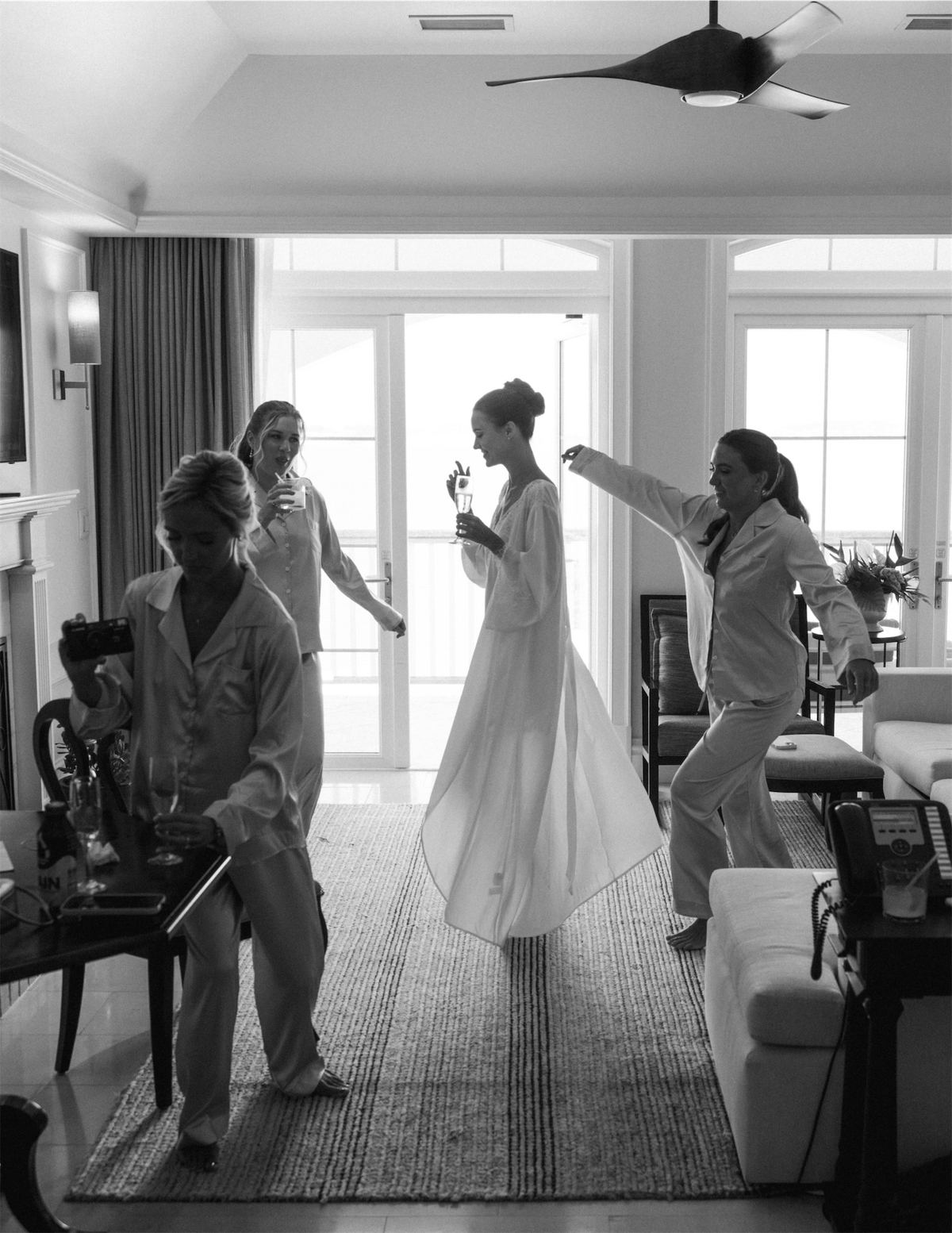 Black and white of the bride twirling in her gown while friends get her ready