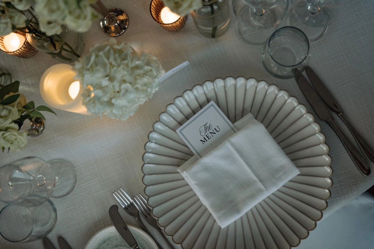 Scalloped plate, menu card and candlelight on the reception table at Rosewood Bermuda
