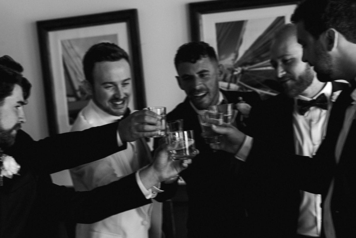 Groom and groomsmen toasting beer bottles before Bermuda wedding ceremony