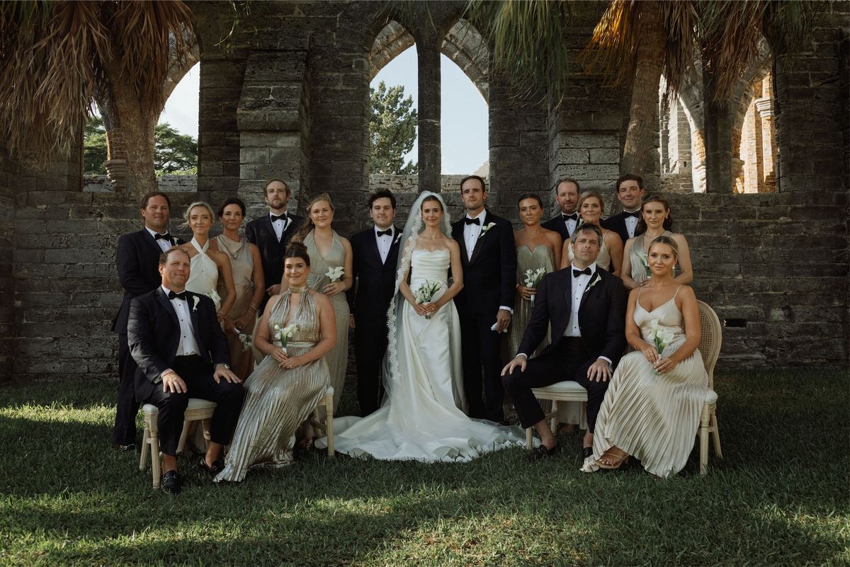 Wedding party portrait seated on the lawn inside the arched church ruins