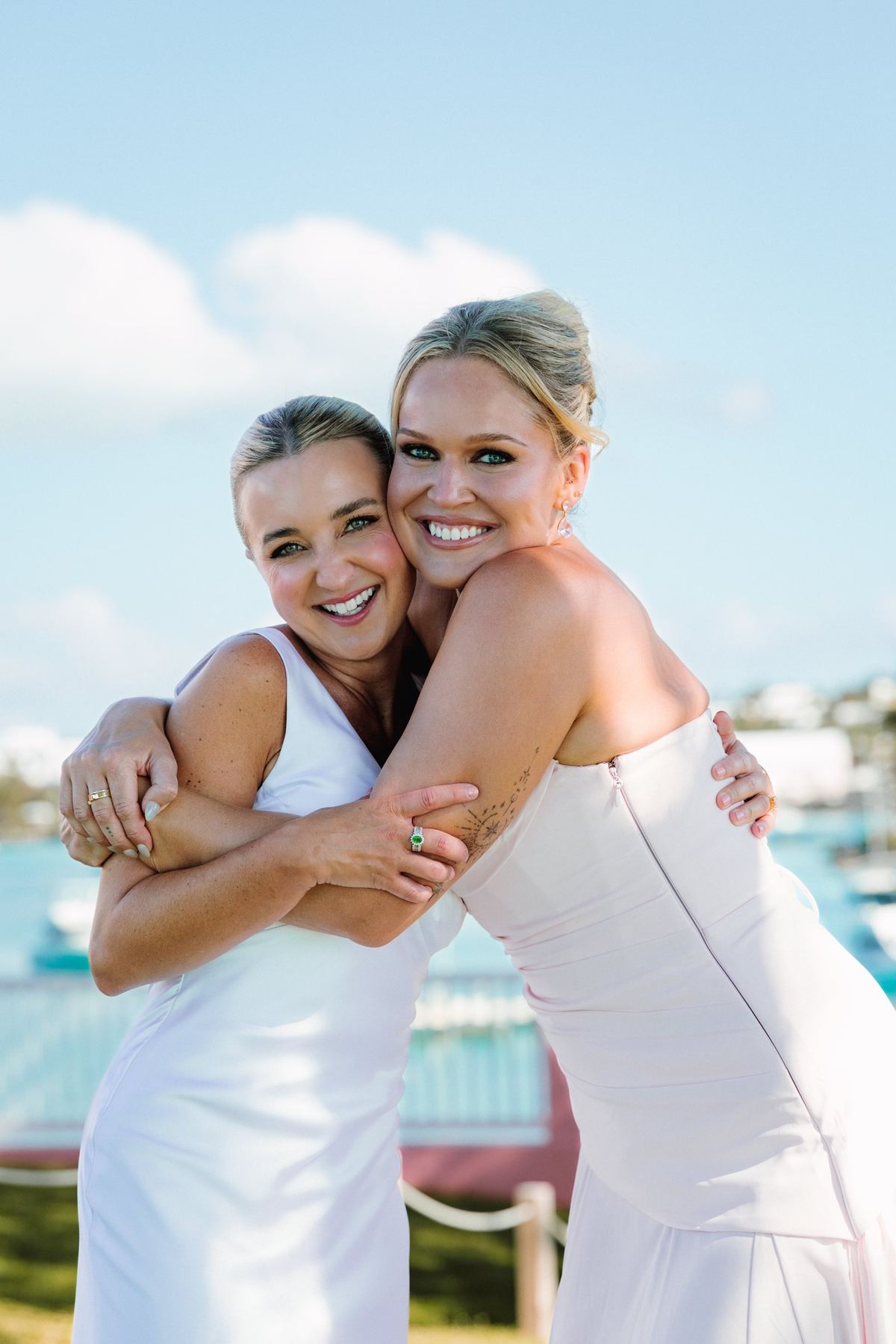 Two brides hugging and laughing together beside the pool at their Bermuda wedding