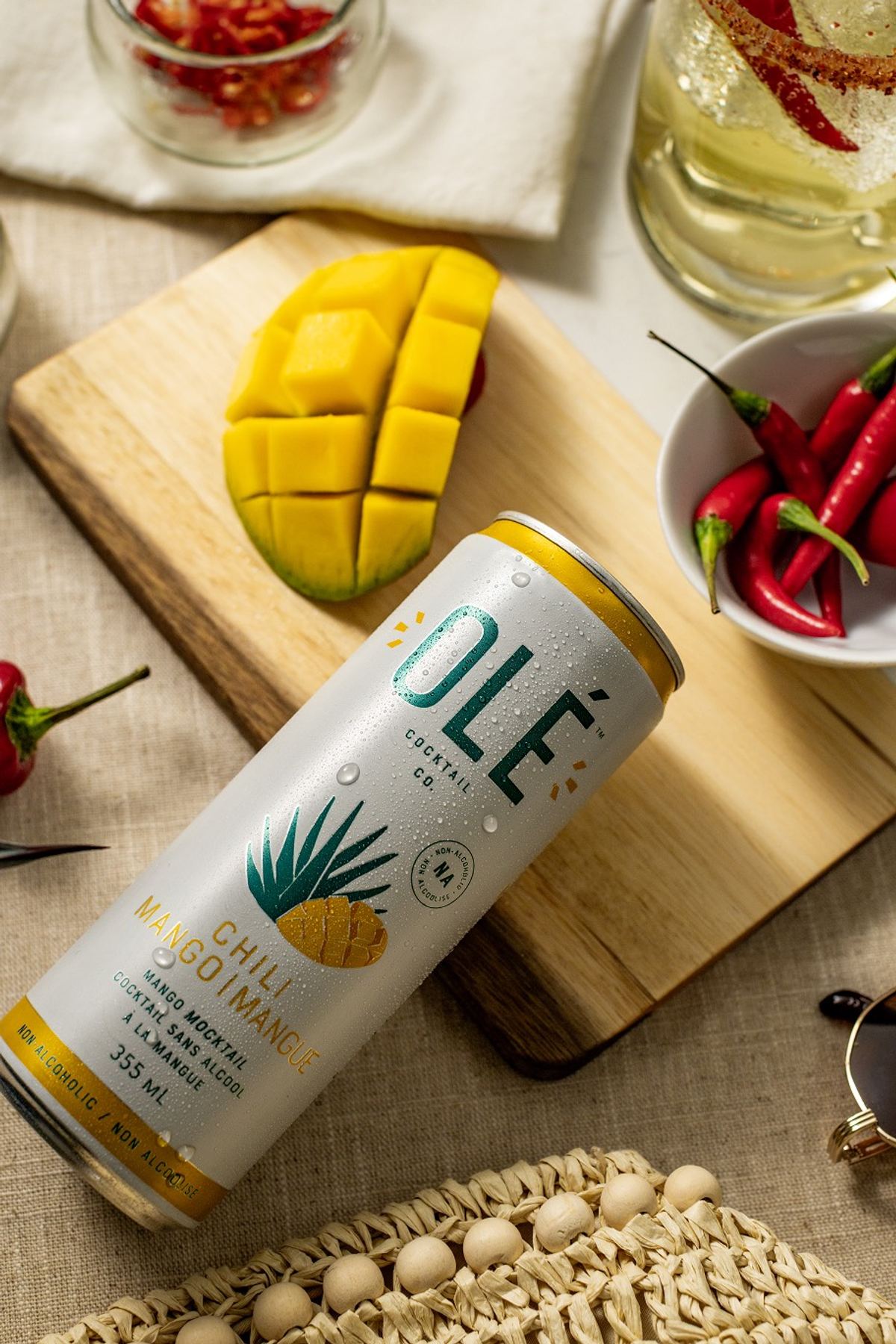Canned cocktail shot from above on a cutting board with fresh mango and red chillies