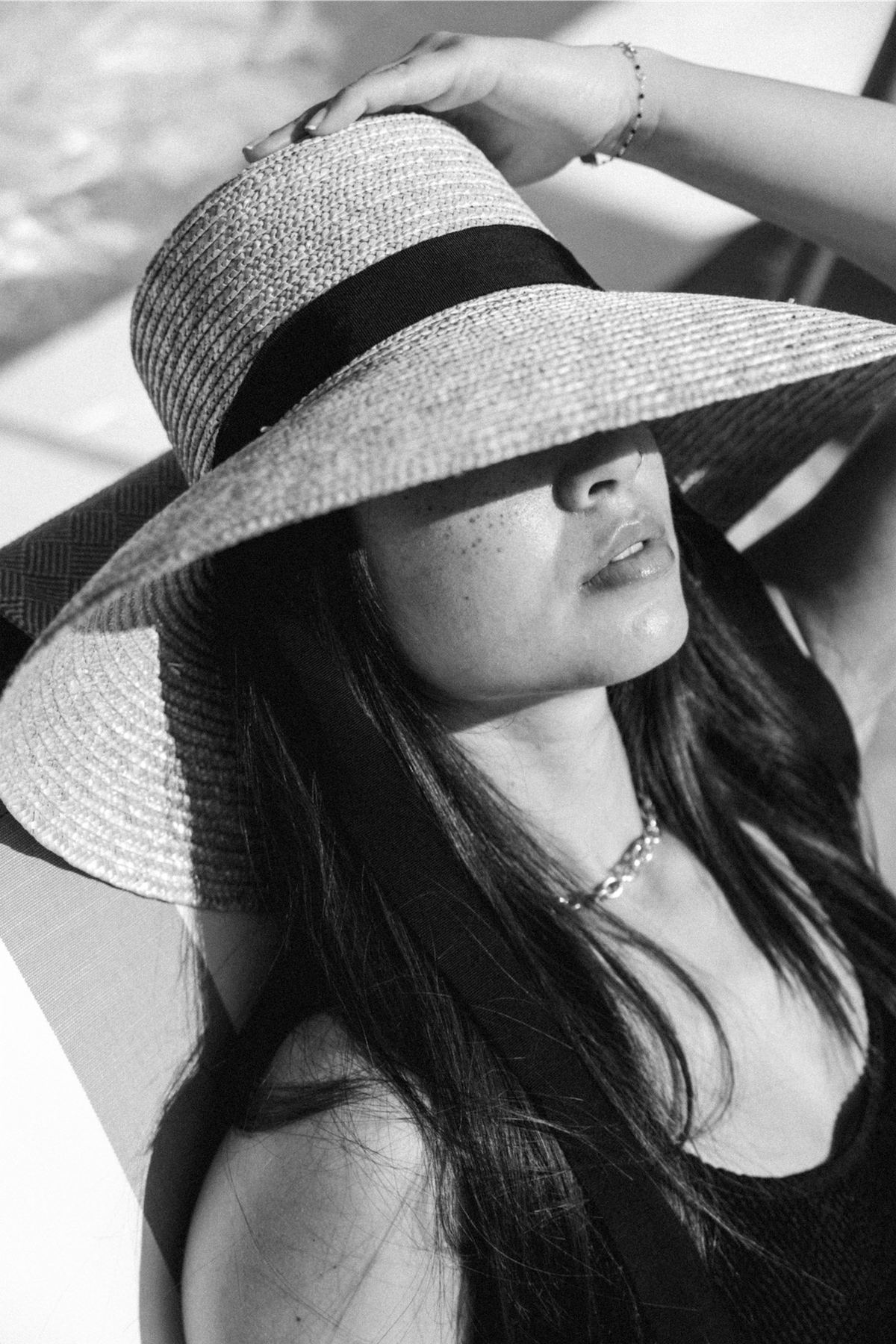Black and white portrait of a model under a wide-brimmed straw sun hat