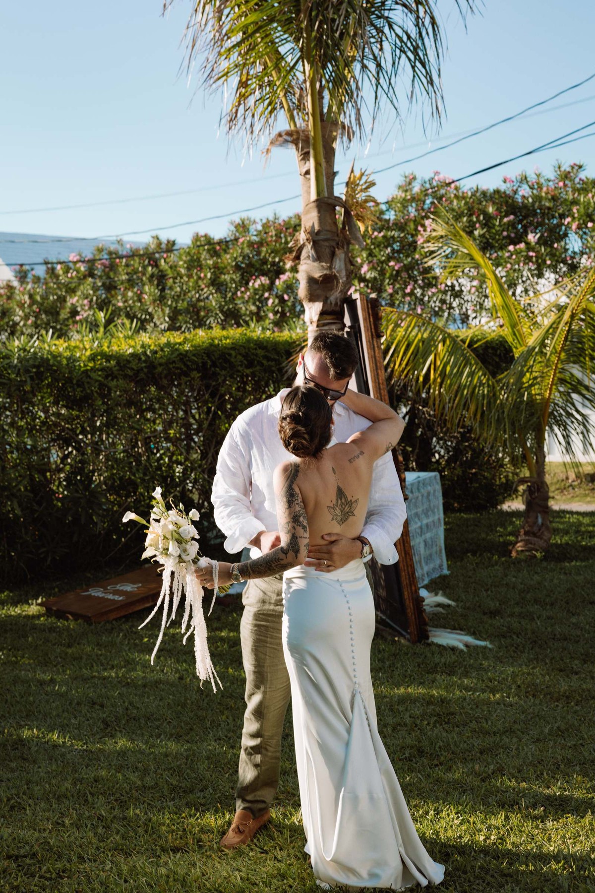 Bride and groom kissing beneath a palm in the late afternoon light