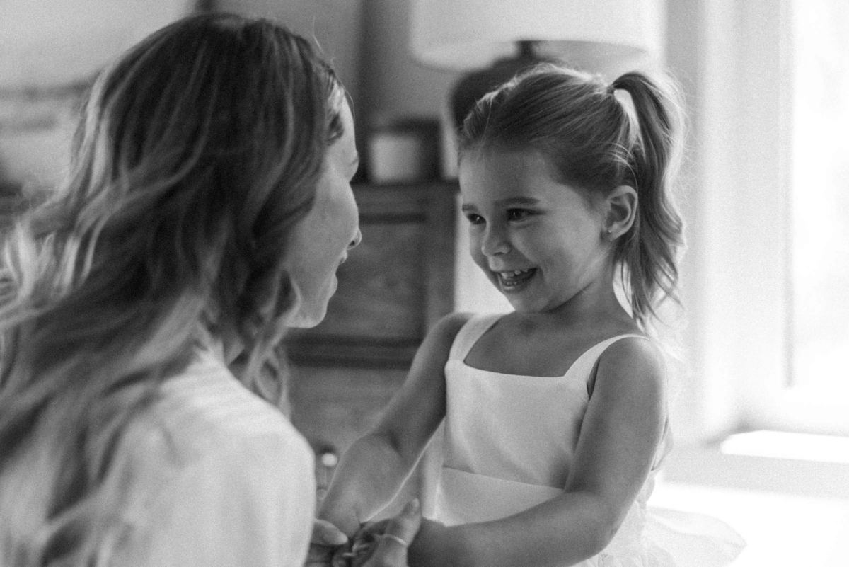 Black and white photograph of the bride laughing nose to nose with the flower girl