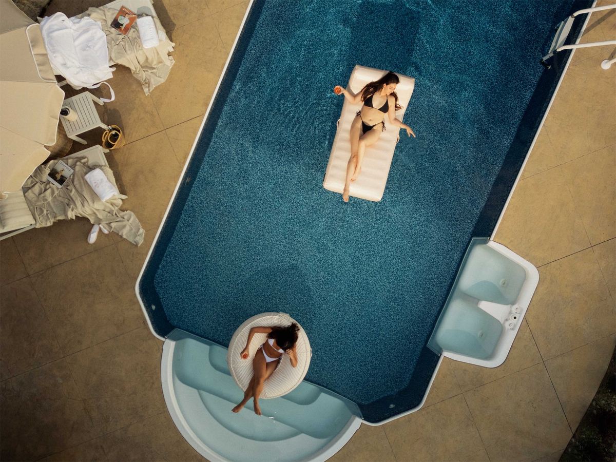 Aerial of a woman floating on a lounger in a deep blue pool