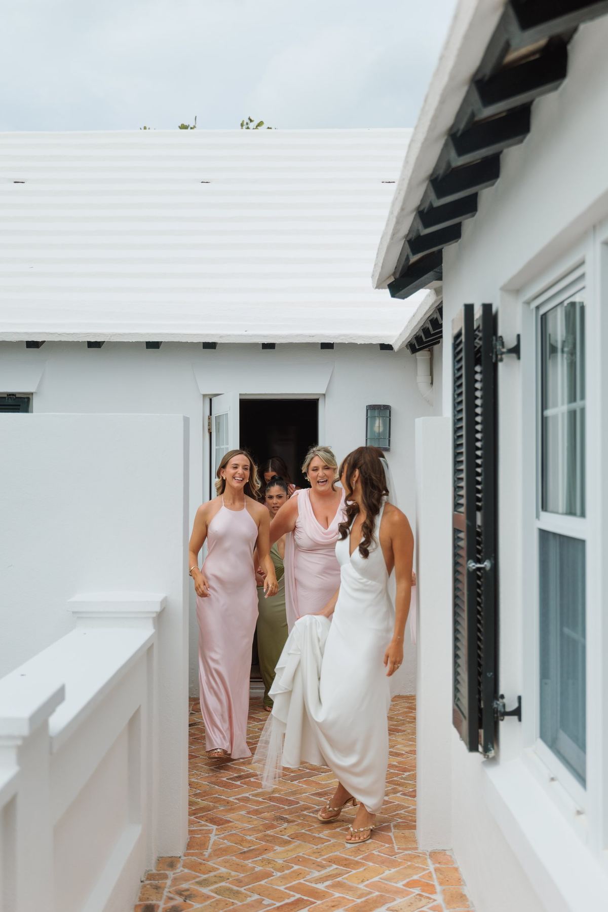 Bridesmaids in pink walking the path to a Bermuda beach ceremony