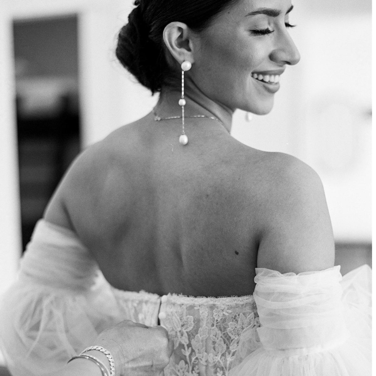 Black and white portrait from behind of the bride's drop earrings and off-shoulder gown