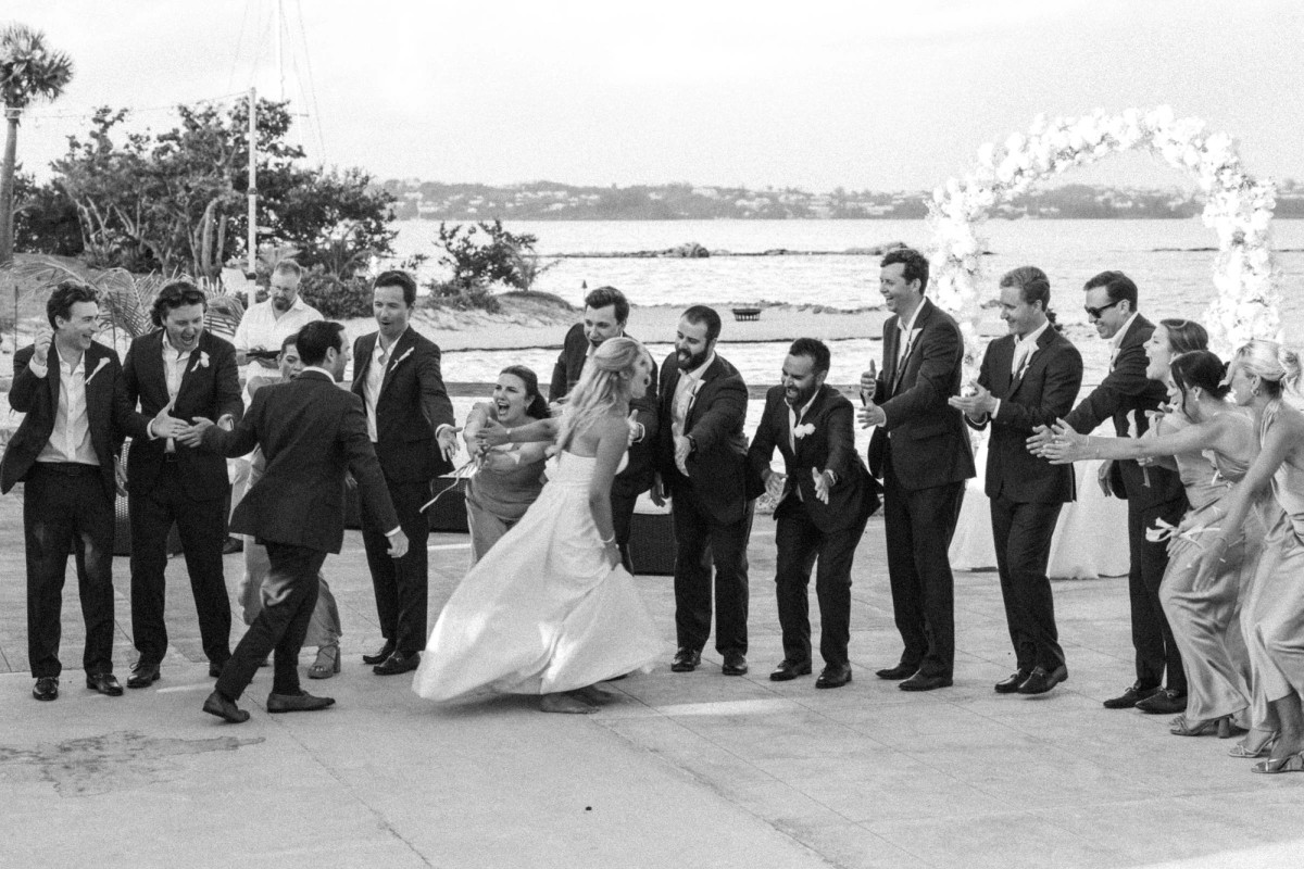 Groomsmen form a line as Paige and Cam dance past on Hawkins Island, Bermuda, black and white