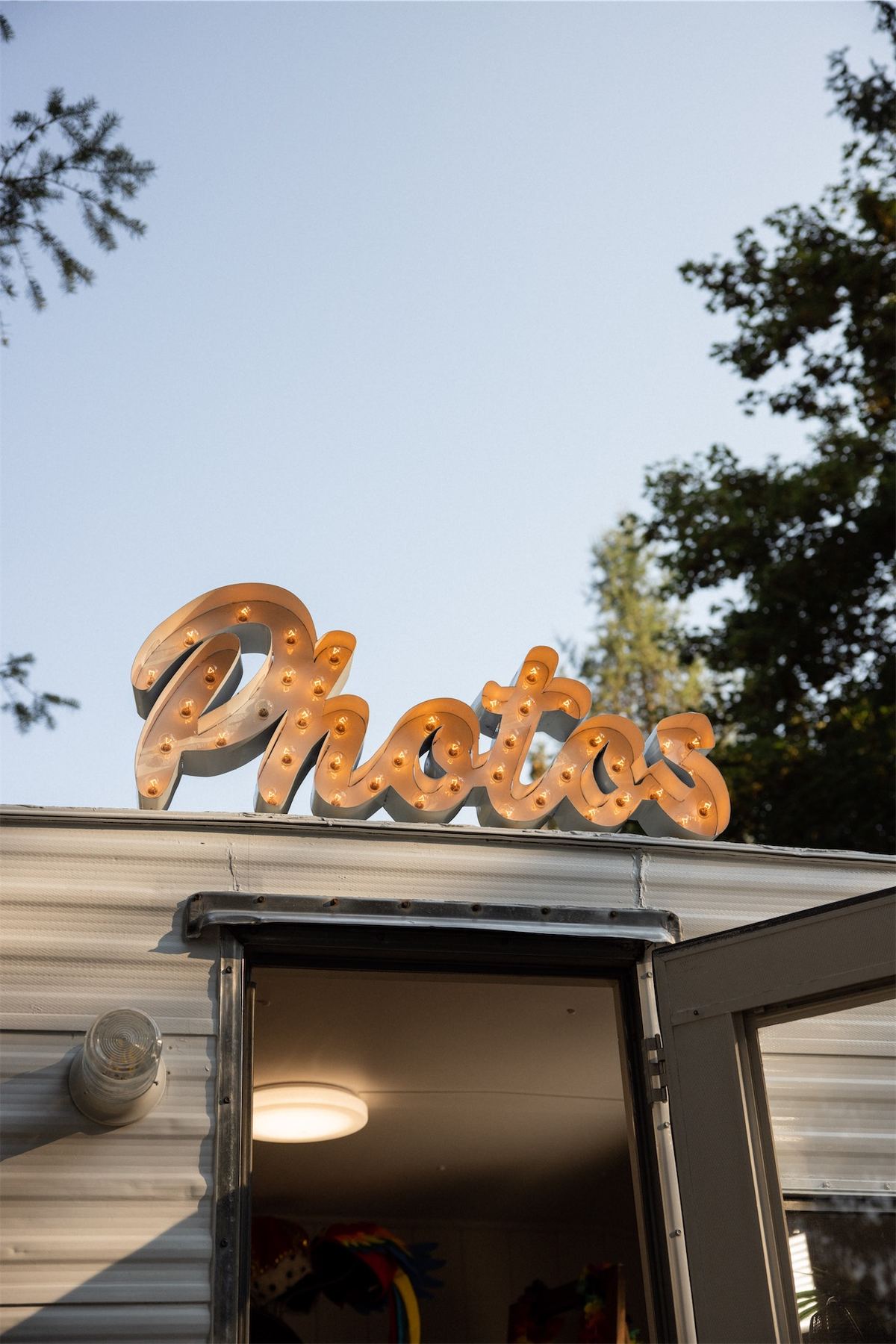 Vintage photo trailer with a gold Photos sign parked at the outdoor reception