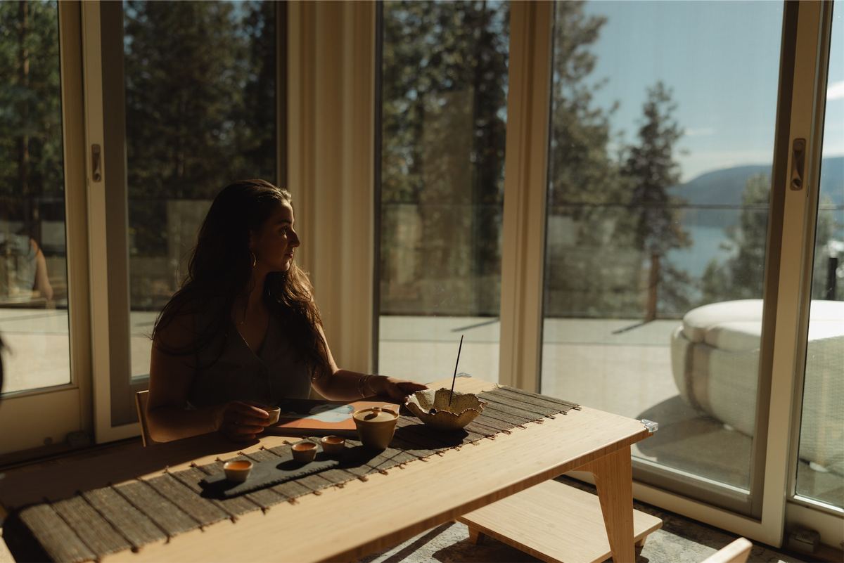 Woman at a low wooden table beside open doors onto the hot tub deck