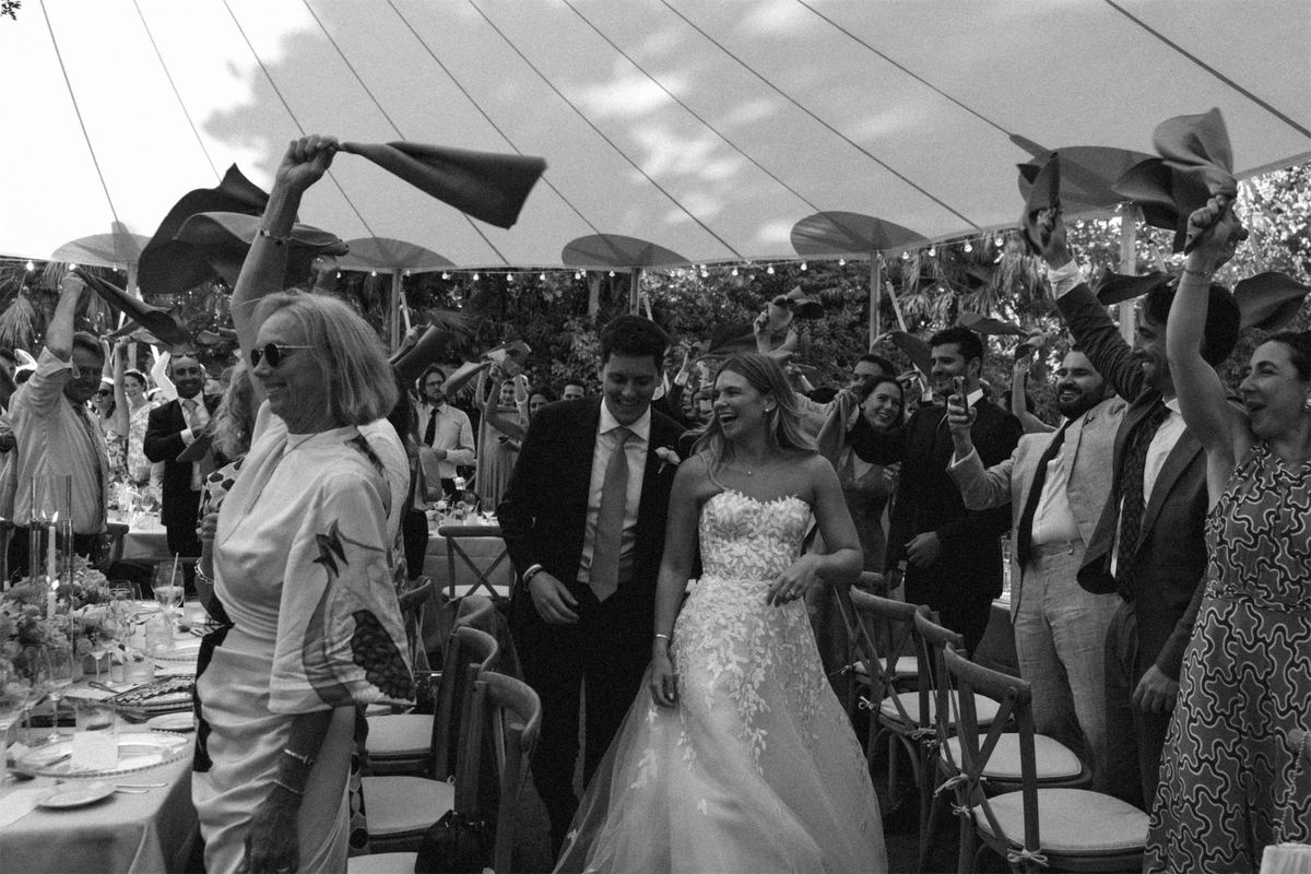 Guests waving napkins around the bride and groom inside the tented reception