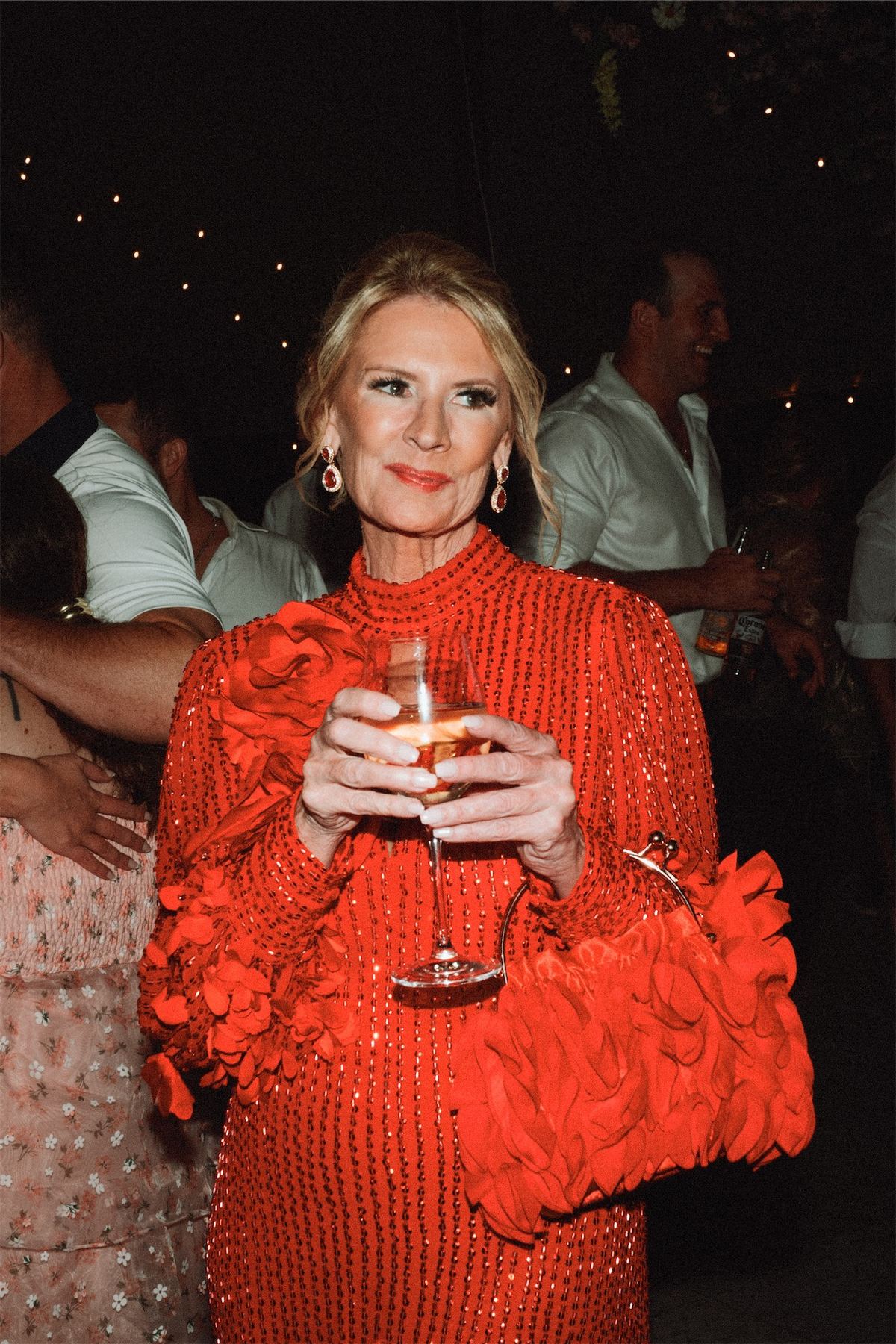 Guest in a red ruffled dress holding a drink at the evening party