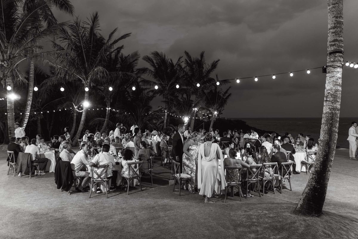 Black and white photograph of the beachfront dinner under string lights at dusk