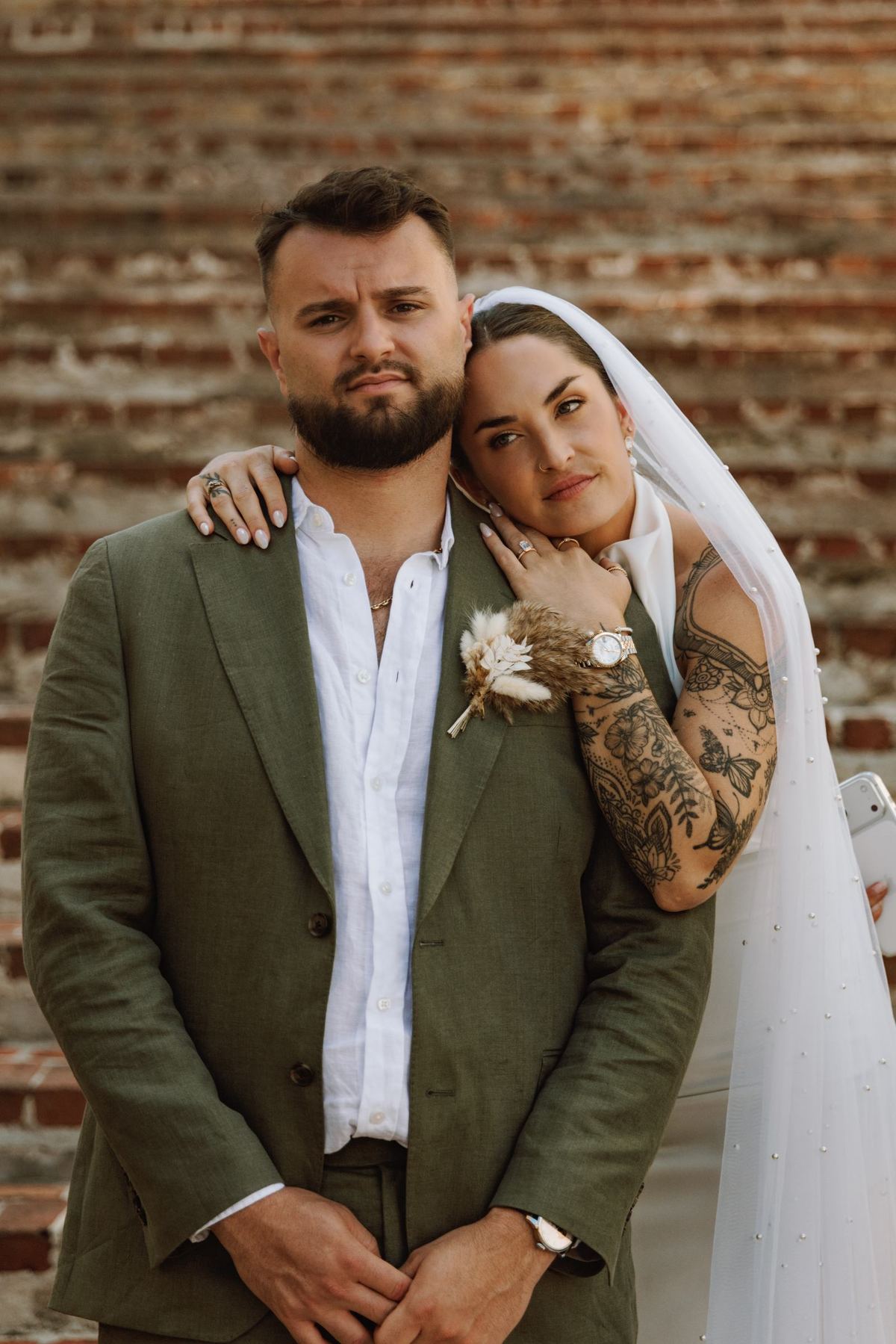 Bride and groom close together against a weathered Bermuda wall