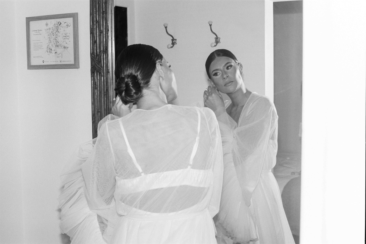 Black and white frame of the bride and a bridesmaid getting ready together in sheer white robes
