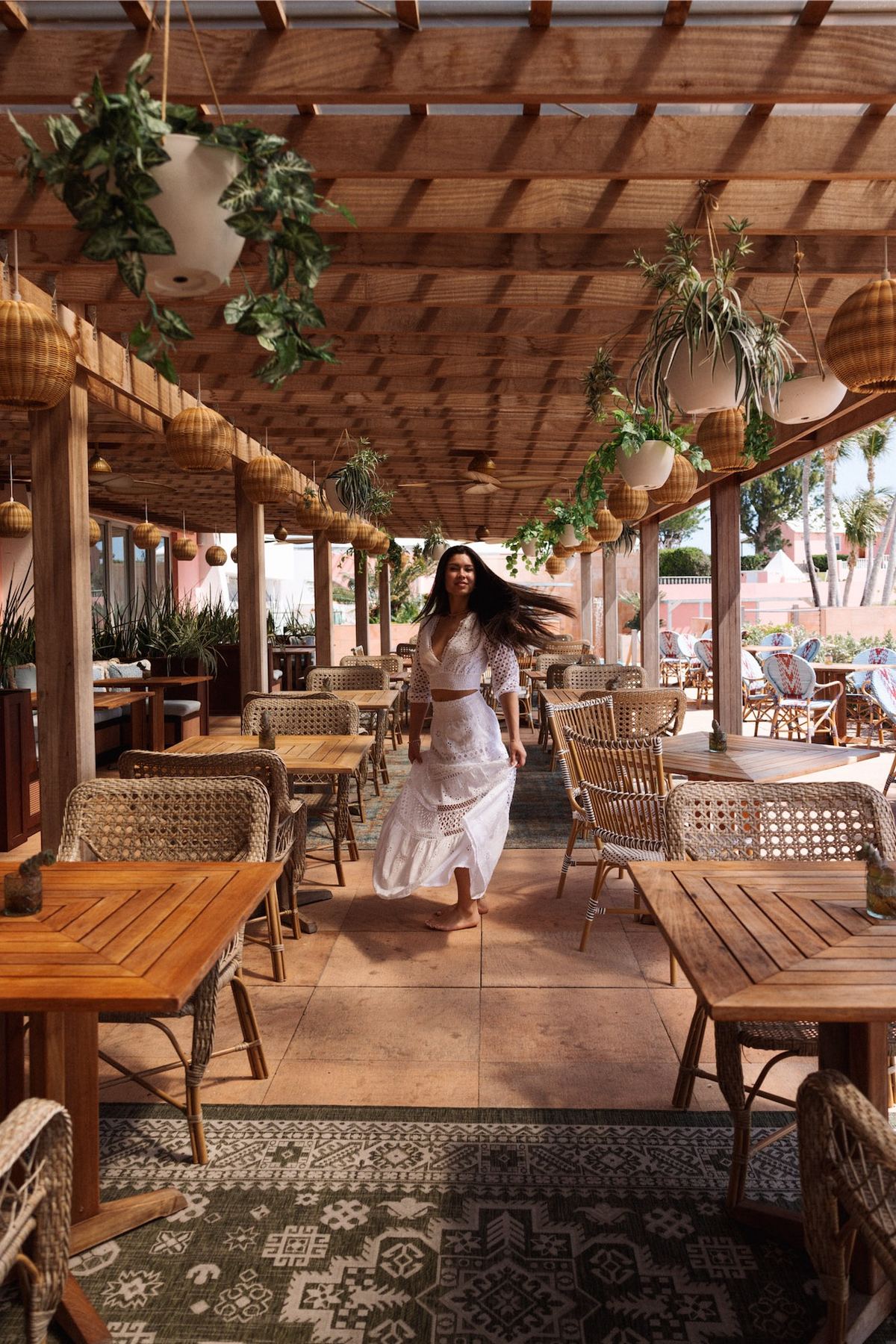 Model walking through an empty pergola-shaded restaurant terrace