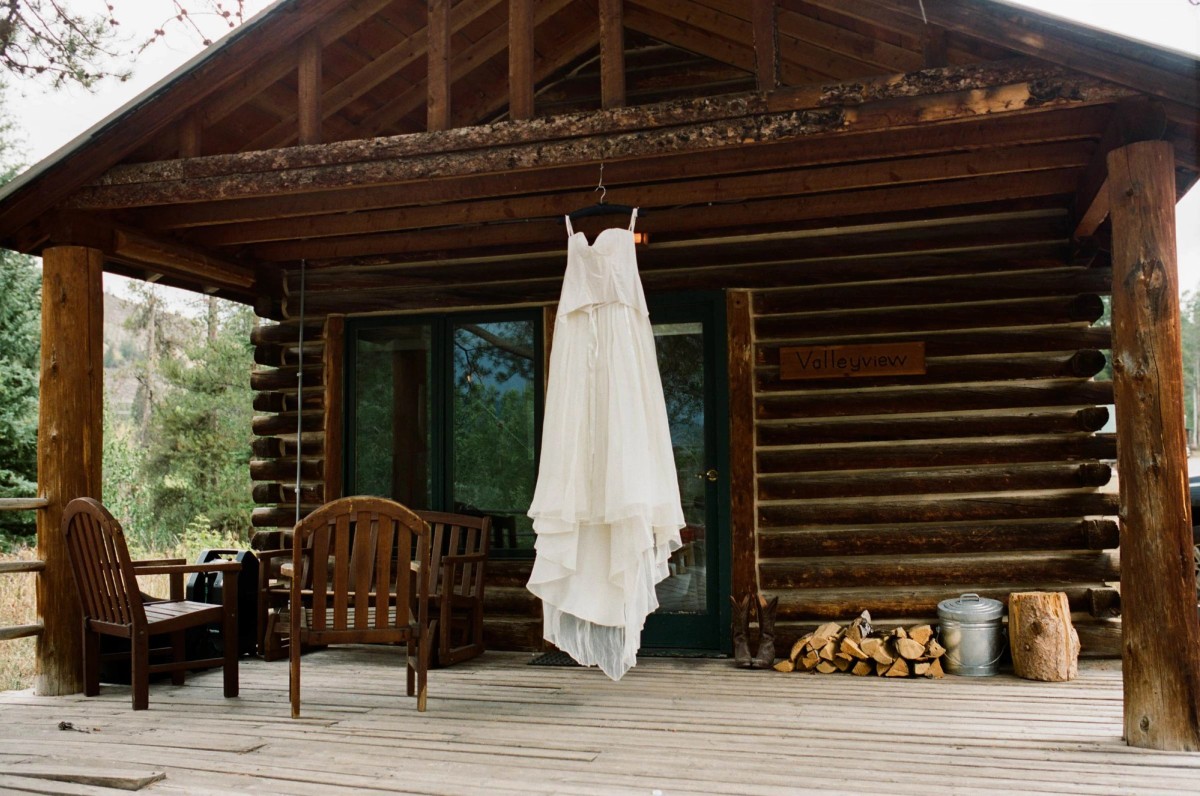 Devin's wedding dress hanging on the porch of the log cabin, shot on film at a mountain ranch among the aspens