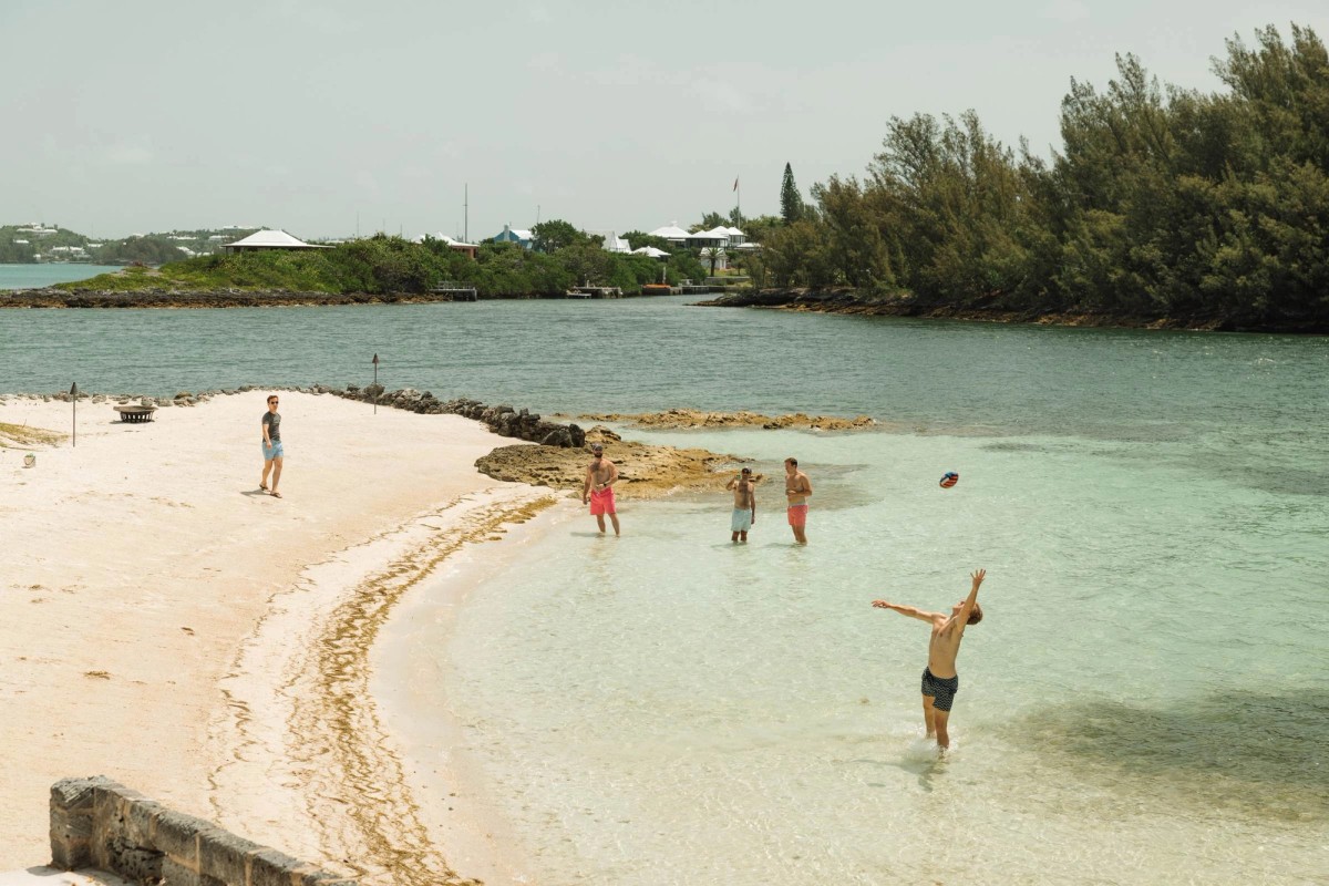 Groomsmen toss a football in the shallow turquoise water on the wedding morning on Hawkins Island, Bermuda