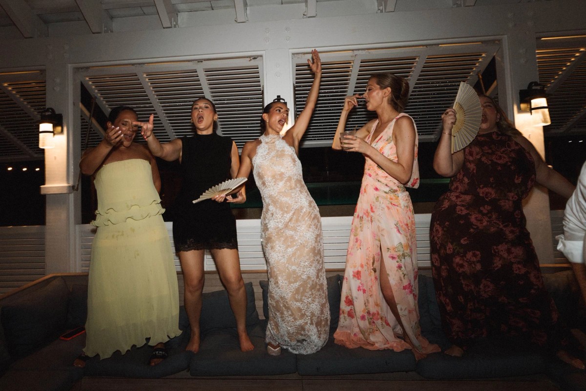Bridesmaids dancing on the banquette in front of the shutters at Rosewood Bermuda
