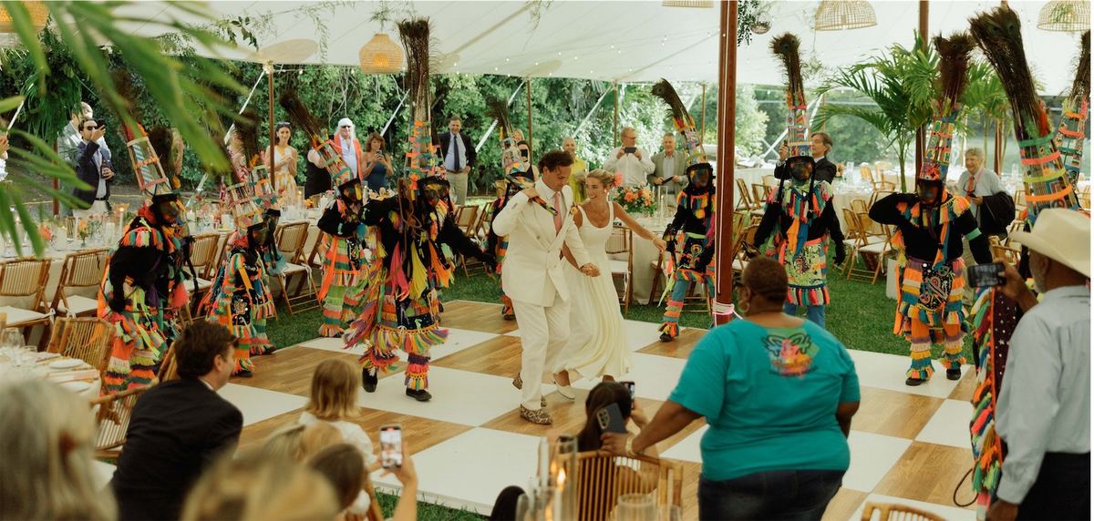 Gombey dancers in feathered costumes performing on the reception dance floor