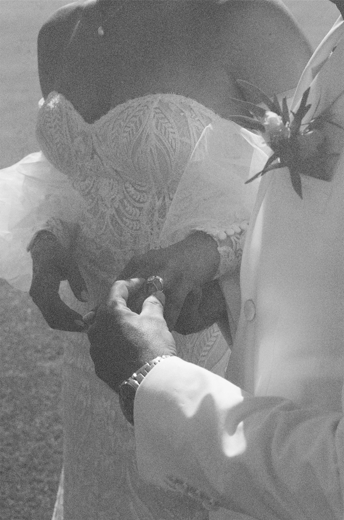 Black and white detail of hands fastening the bride's jewellery before the ceremony