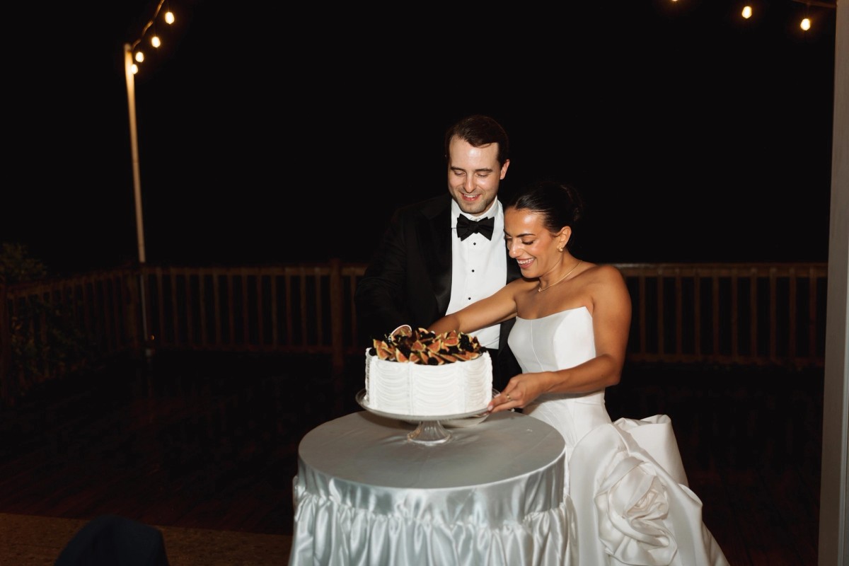 Couple cutting their cake under string lights at night at Rosewood Bermuda