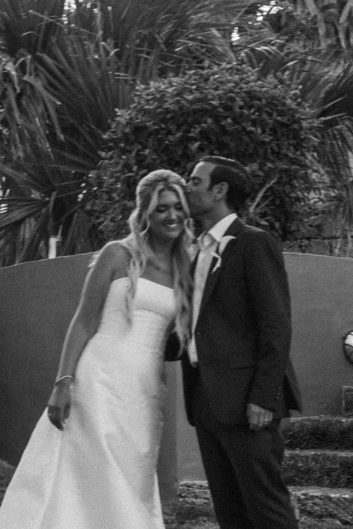Cam kisses Paige's temple among the palms on Hawkins Island, Bermuda, black and white