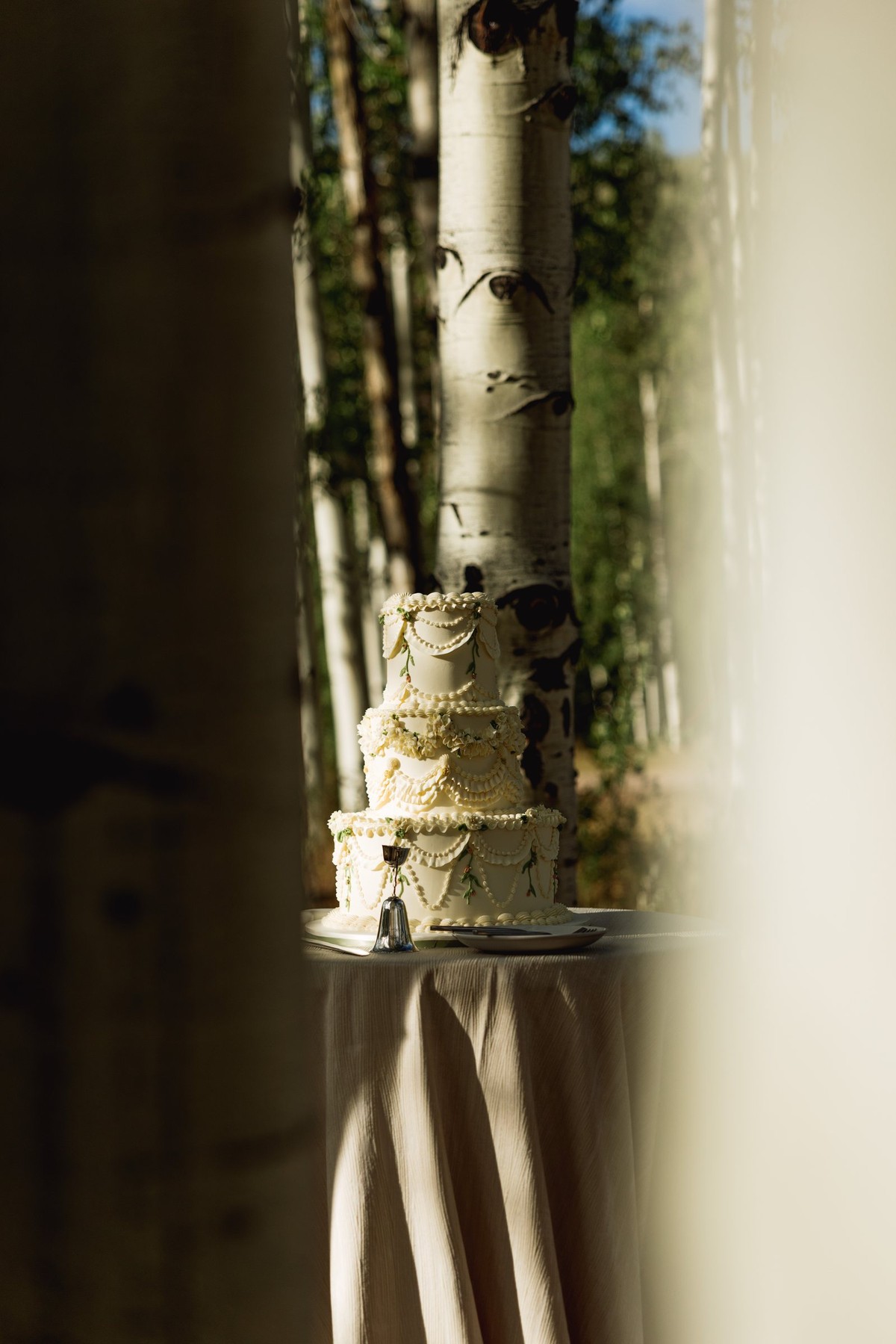 The tiered wedding cake glowing between the aspens at a mountain ranch among the aspens