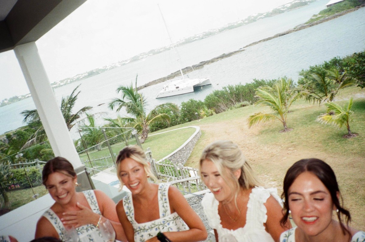 Bridesmaids laugh on the porch over the bay on the wedding morning on Hawkins Island, Bermuda, on film