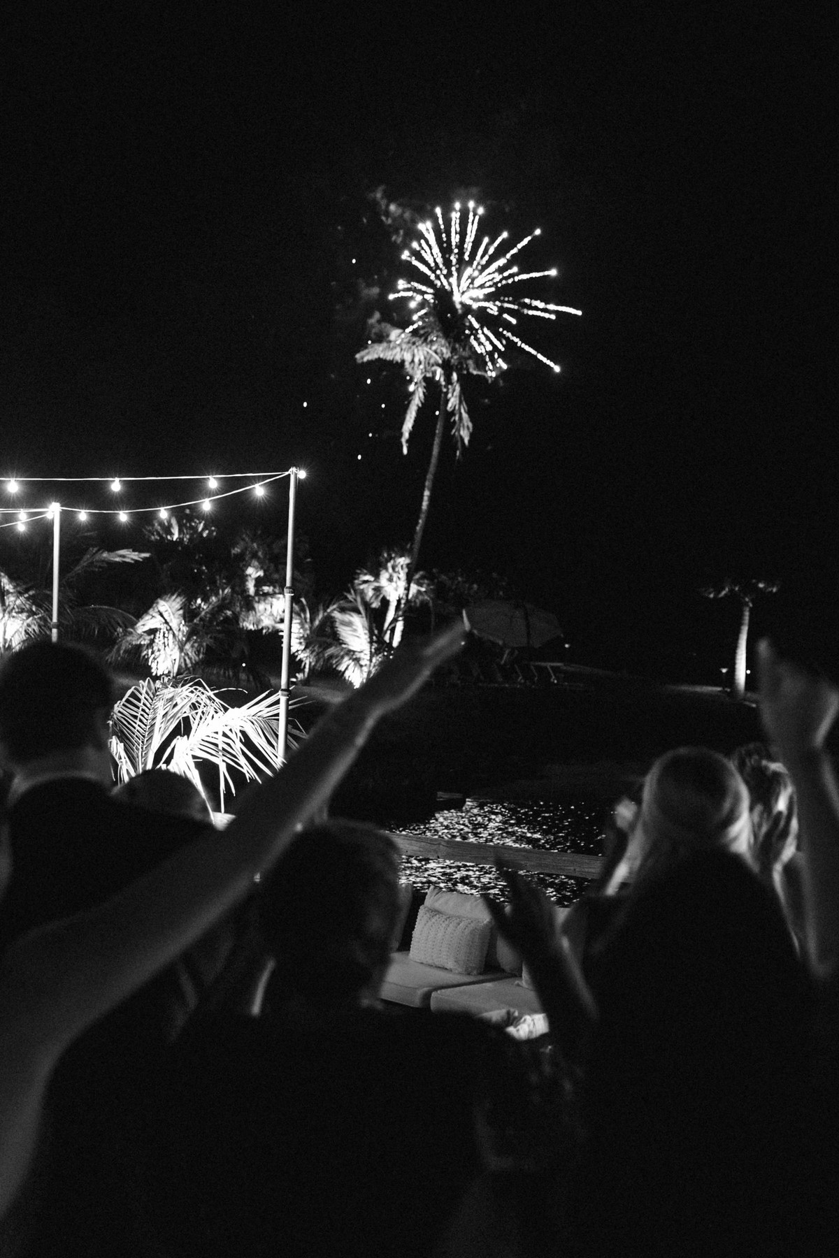 Fireworks burst over the string lights and the crowd on Hawkins Island, Bermuda, black and white