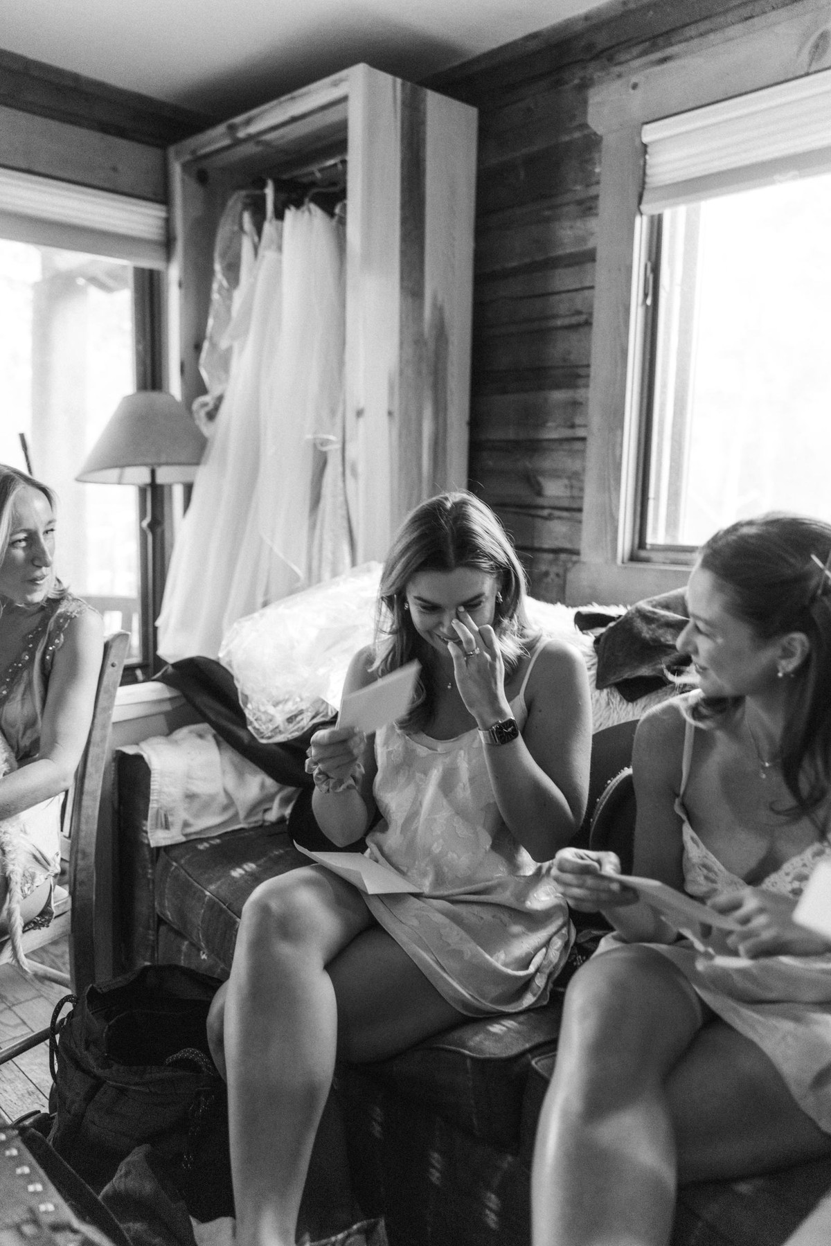Devin laughing with her bridesmaids on the sofa while getting ready at a mountain ranch among the aspens, black and white