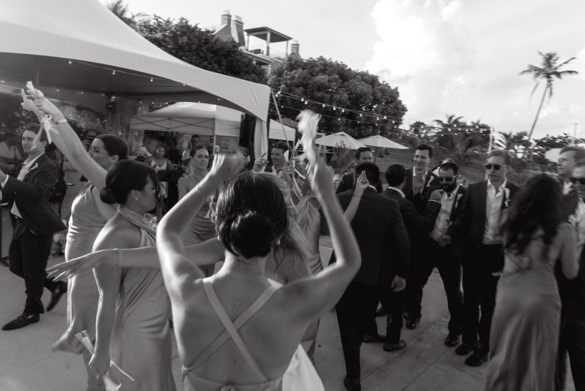 Bridesmaids throw their hands up on the dance floor on Hawkins Island, Bermuda, black and white