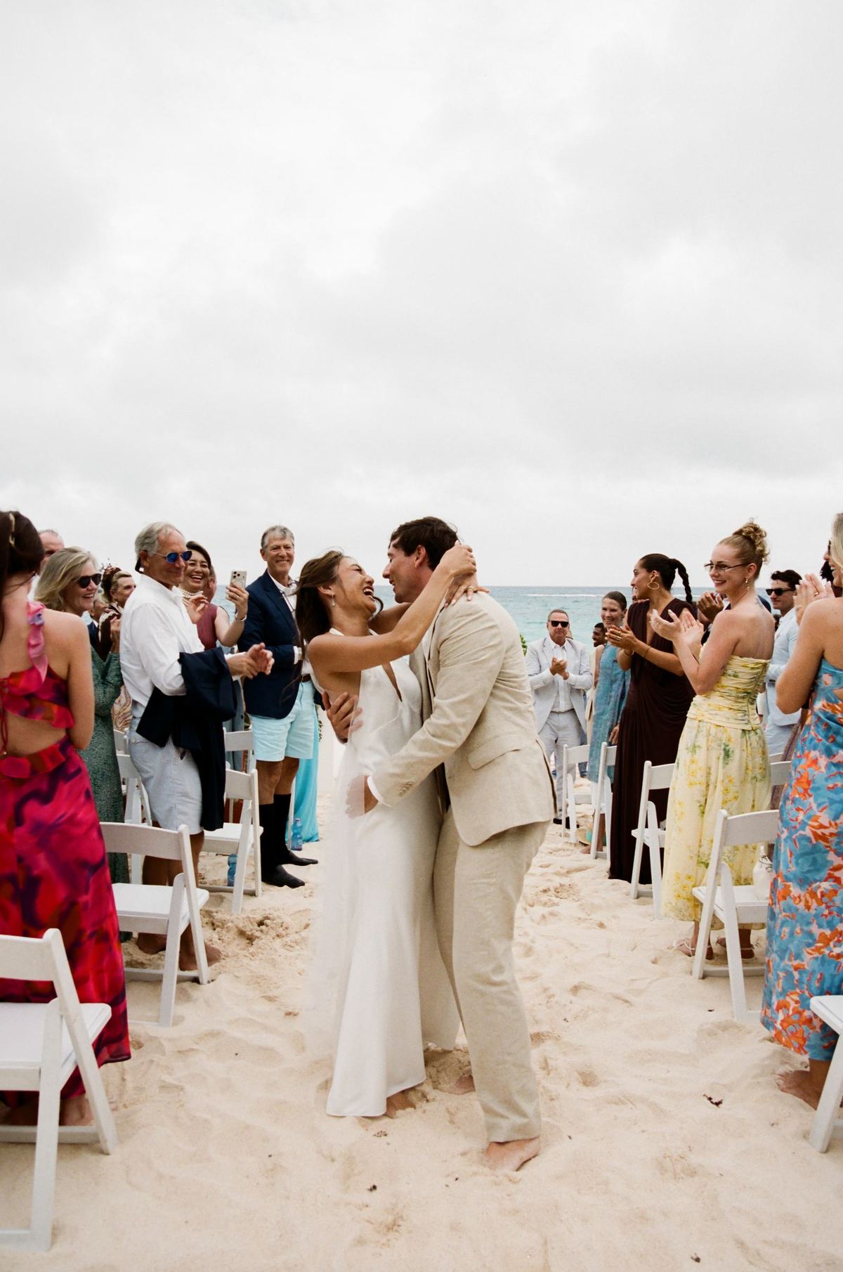 Bride and groom walking the recessional across the sand as guests cheer