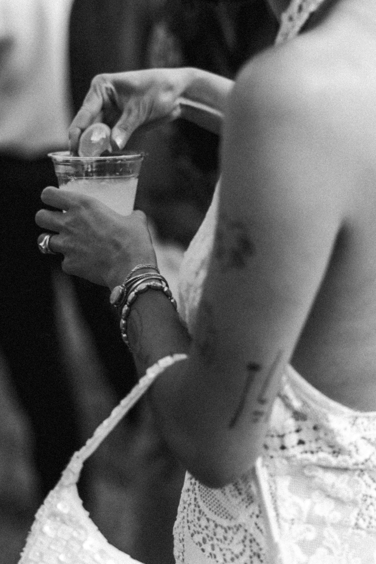 Devin's tattooed arm and bracelets as she takes a drink at a mountain ranch among the aspens, black and white
