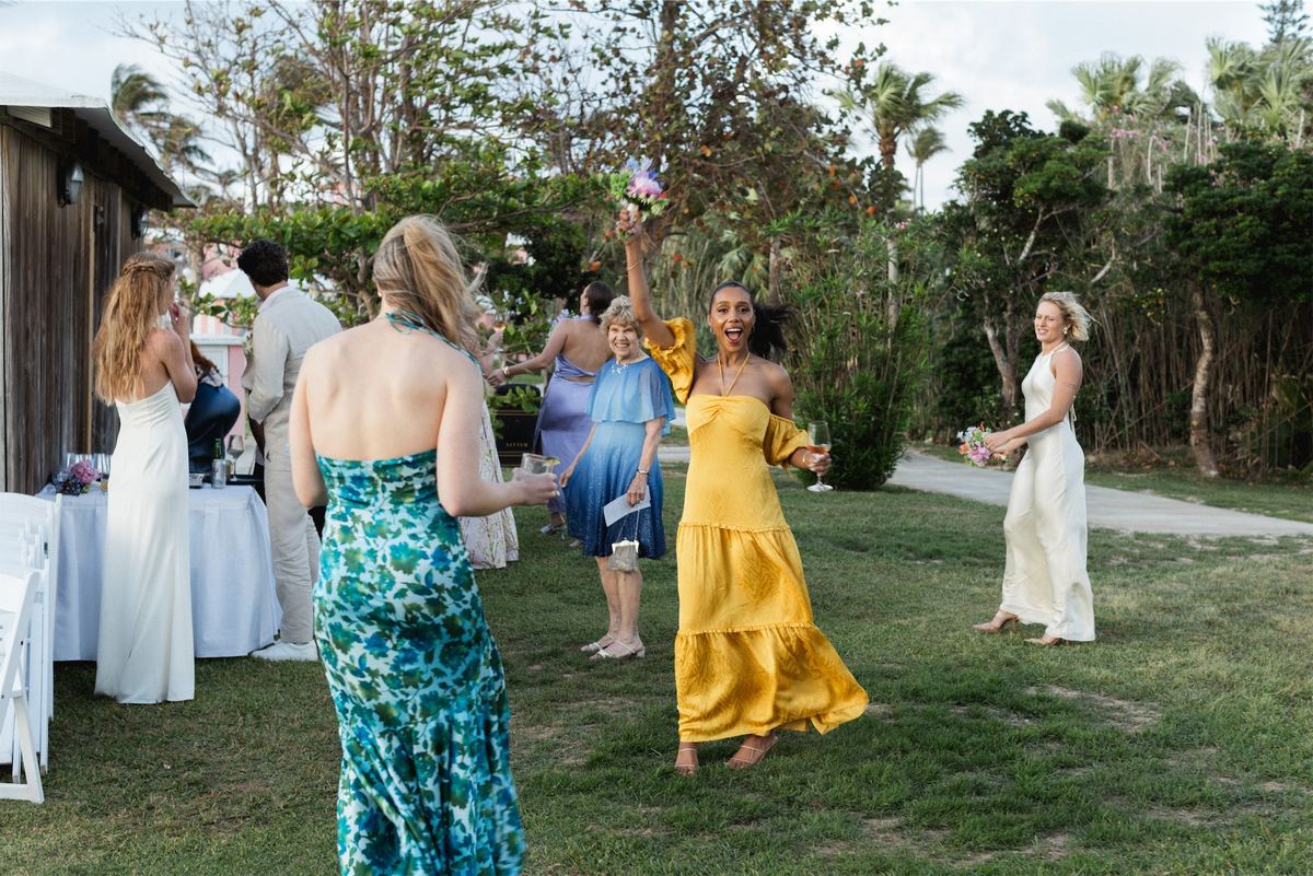 Bridesmaids in bold colours cheering as the bride crosses the garden lawn