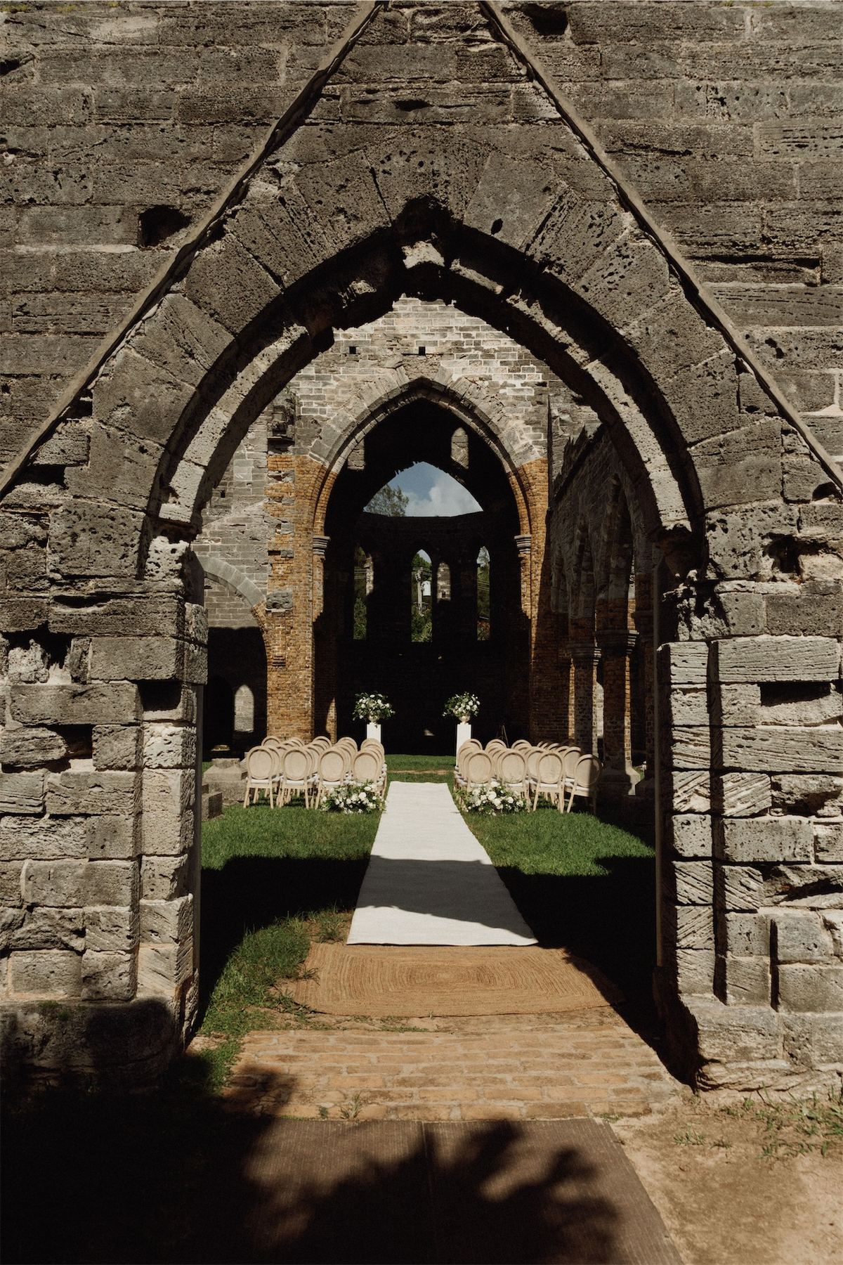 Ceremony aisle framed by the gothic arch of the roofless church