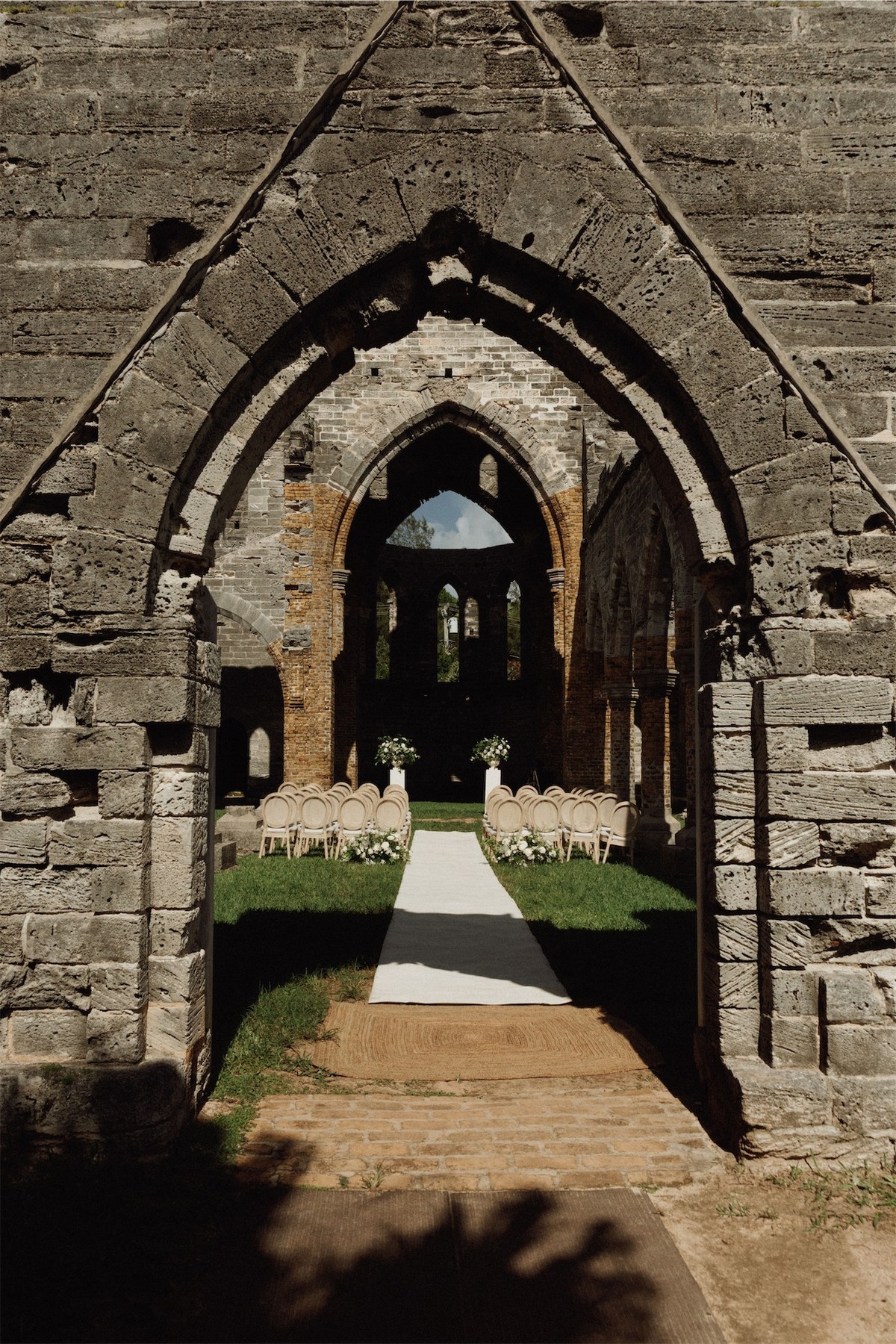 Ceremony aisle framed by the gothic arch of the roofless church