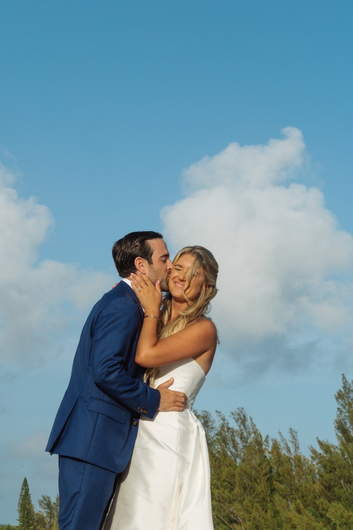 Cam kisses Paige's cheek under a deep blue sky on Hawkins Island, Bermuda