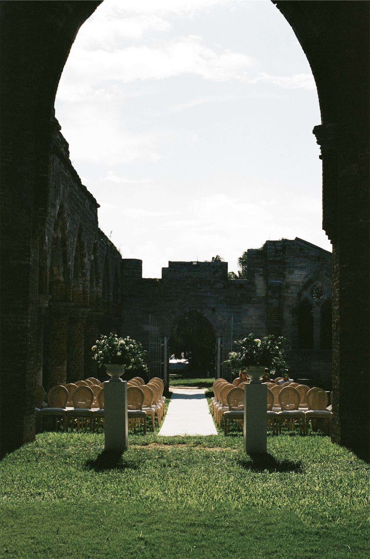 Ceremony aisle seen through a stone keyhole opening in the ruined wall