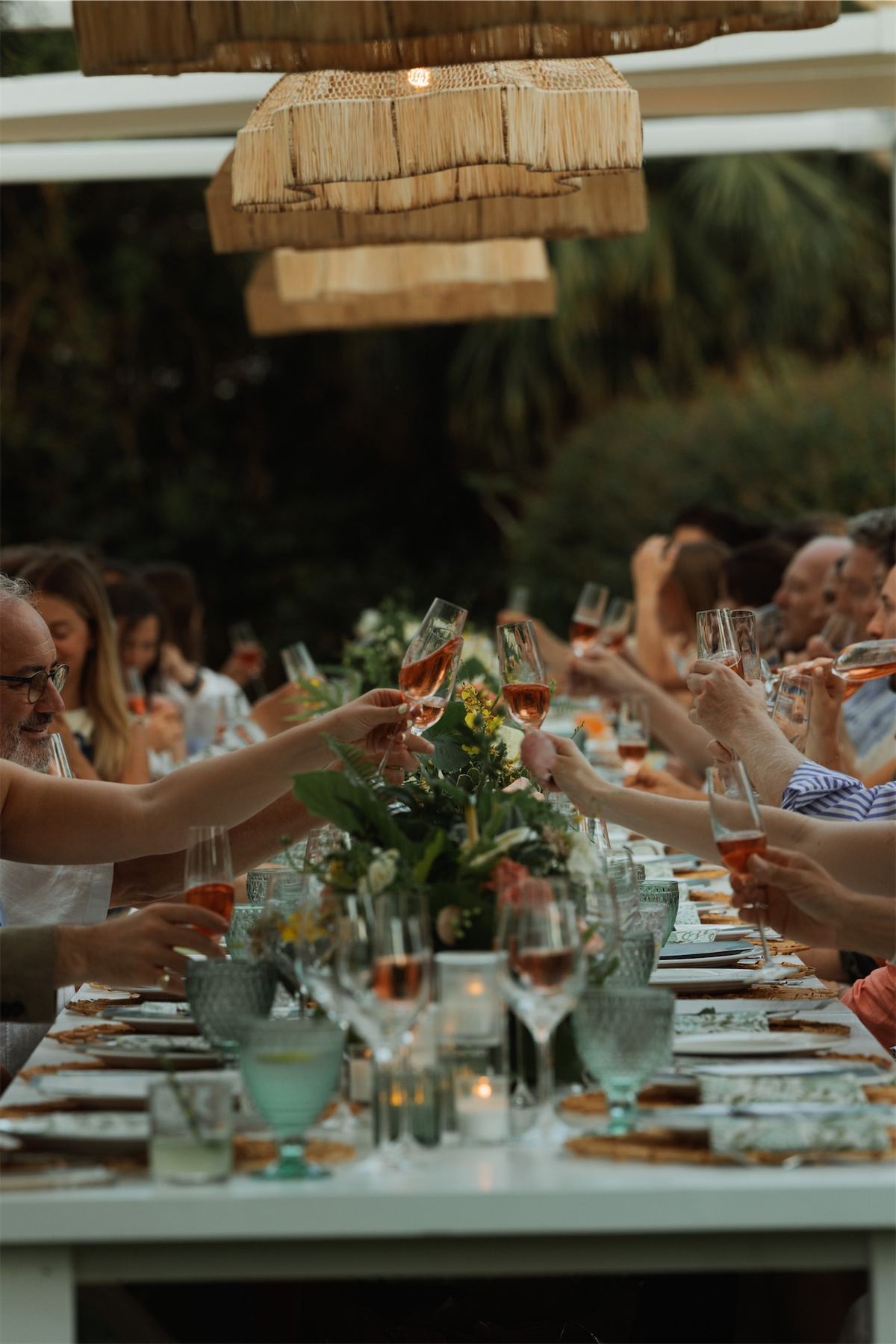Guests reaching across a candlelit table to clink glasses at the reception