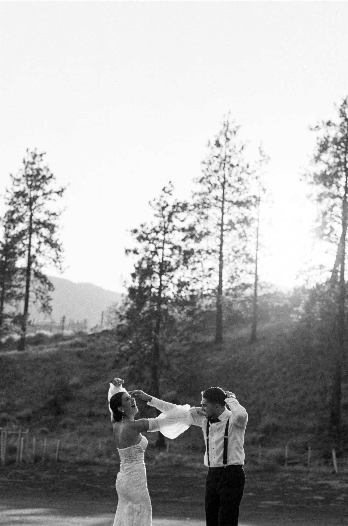 Black and white wide frame of the couple dancing on a hillside at dusk