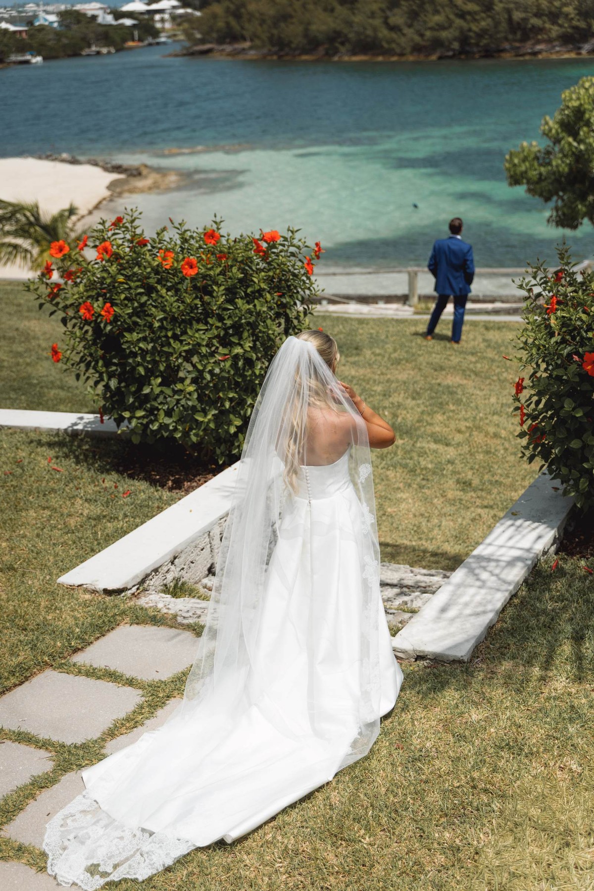 Paige walks toward Cam as he waits with his back turned by the water on Hawkins Island, Bermuda